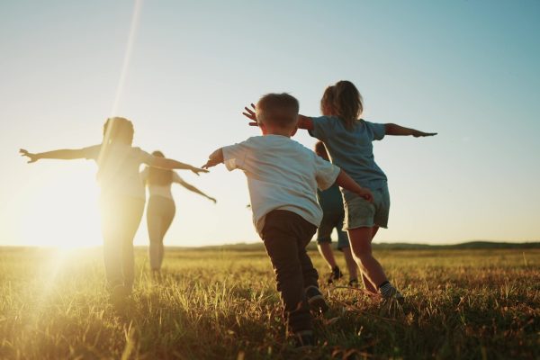 kids run in the park at sunset. friendly family children camp kid dream concept. a group of children run on the grass at rays fun of the sun silhouette. childhood dream teamwork sunset concept